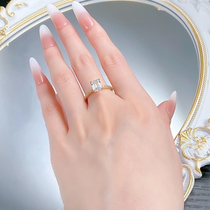 Close-up of golden rectangular emerald-cut zircon ring worn by a model in a luxury setting
