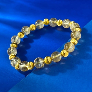 Dettaglio di perle di citrina gialla da 8mm e ciondoli in oro testurizzati sul braccialetto