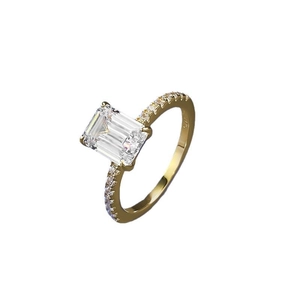 Elegant gold ring with emerald cut crystal and side stones on a clean white background