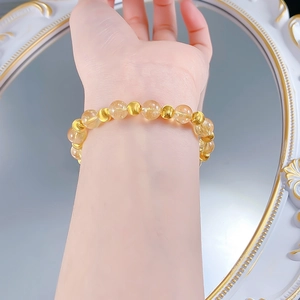 Dettaglio delle perle di citrino da 8 mm e delle sfere dorate su un elegante bracciale