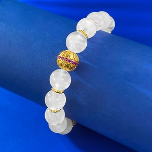 Macro view of moonstone beaded bracelet with intricate gold-plated hollow charms