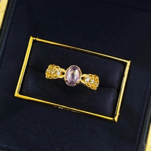 Detail of vintage hollow out gold ring with oval purple gemstone in a jewelry box