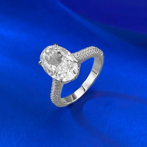 Macro shot of oval-cut crystal solitaire ring with pavé diamonds on high-end silver band