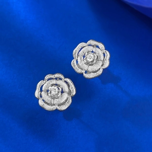 Silver brushed camellia stud earrings with sparkling cubic zirconia on blue velvet