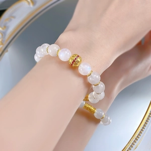 Detail of S925 silver moonstone bracelet with gold filigree bead and red gemstone accents