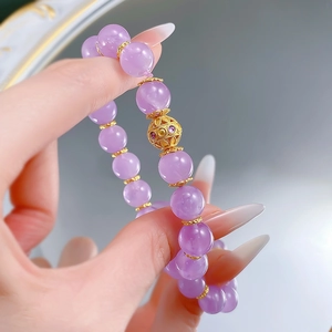 Elegant 10mm lavender amethyst bead bracelet with a gold hollow charm on a female wrist