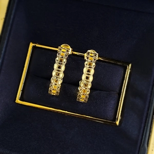 Close-up of S925 gold-plated drop earrings with hollow coin pattern on blue velvet
