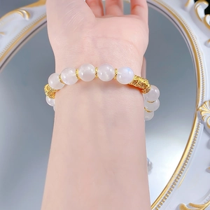 Macro shot of S925 silver moonstone bracelet with golden hollow floral beads on wrist