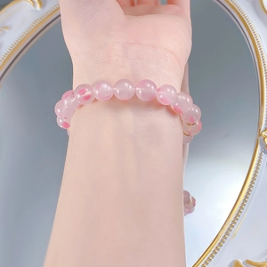 Close-up of 9.0mm cherry blossom pink quartz beads with golden spacers on a wrist