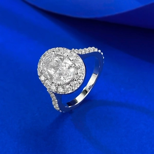 Macro detail of oval cut halo diamond ring with pavé band on silk background