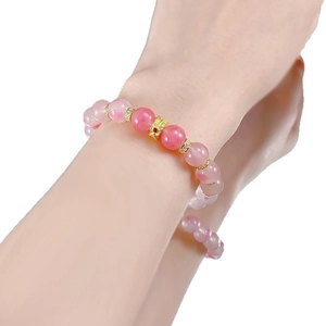 Pink sakura crystal beaded bracelet with hollow gold charms worn on a female wrist