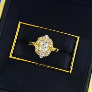 Luxury gold ring with rectangular emerald cut diamond and halo set in blue box