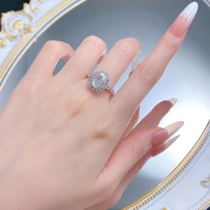 Luxurious halo oval cut diamond ring with pavé band worn in front of a mirror