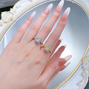 Detailed view of silver and gold halo rings with emerald cut diamonds on a mirror surface