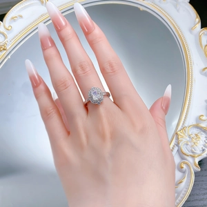 Detail of a radiant cut diamond ring with halo setting worn on a hand near a mirror