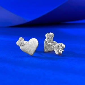 Détail macro de boucles d'oreilles cœur en argent avec finition mate brossée et fermoirs papillon