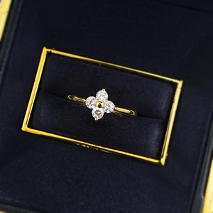 Macro shot of a gold four-leaf clover ring with zircon stones in a blue velvet box