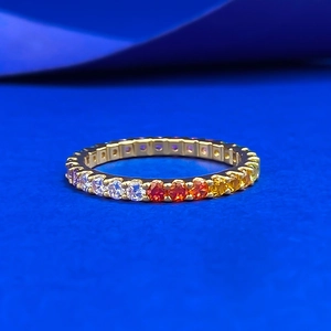 Regenbogen-Eternity-Ring mit bunten Edelsteinen und goldener Fassung auf blauem Grund