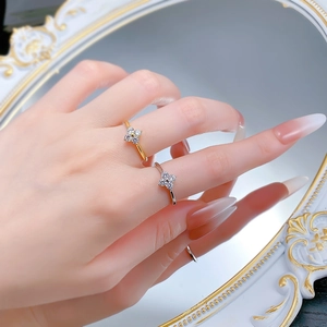 Detail of silver and gold clover rings with zircons worn on hand against a mirror