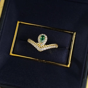 Elegant V-shaped gold ring with pear-cut emerald gemstone and pave diamonds in velvet box