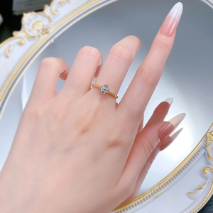 Detail shot of a golden four-leaf clover ring with sparkling zircon stones on model finger