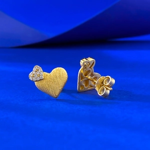 Detailed macro view of gold-plated heart earrings with brushed finish and zircon accents
