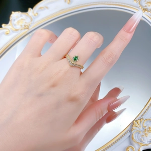 Detailed view of V-shaped gold ring with pear-cut green emerald and pave diamonds