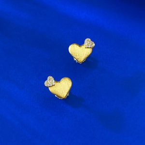 Detailed macro of S925 heart earrings with brushed gold finish and pavé zircons