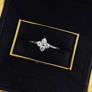Top-down macro of S925 silver four-leaf clover ring with clear gems in a luxury jewelry box