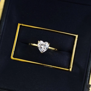 Macro view of heart-cut diamond ring with gold band in a blue velvet gift box