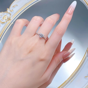 Détail d'une bague en argent avec diamant en forme de cœur portée sur un fond de miroir chic