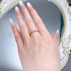 Nahaufnahme des Regenbogen-Edelsteinrings mit rosa und grünen Kristallen an der Hand