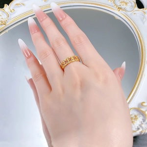 Nahaufnahme eines goldfarbenen Rings mit roten Zirkonsteinen an einer Hand