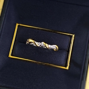 Makro-Detail des verschlungenen Gold- und Silberschlangenrings mit Pavé-Steinen in Box