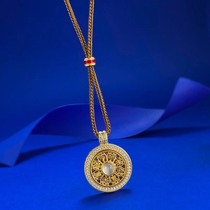 Detail of S925 silver compass pendant with white stone on a gold woven cord
