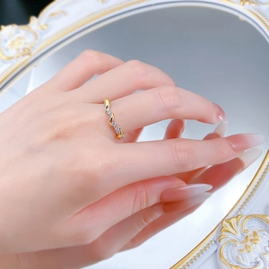 Detail eines gedrehten Goldrings mit Pavé-Diamanten auf elegantem Spiegelhintergrund