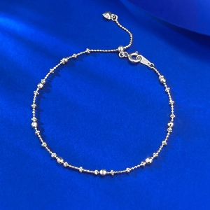 Macro view of S925 sterling silver beaded bracelet with heart charm on blue silk