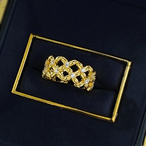 Bague fleurie dorée ajourée avec zircons brillants sur fond de boîte à bijoux bleue
