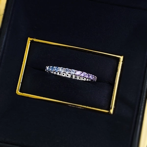 Detail of gradient blue to purple gemstones in a silver pave ring on a black velvet box