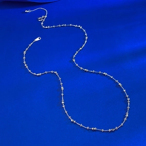 Detail of S925 silver link chain necklace with flower motifs on blue silk background