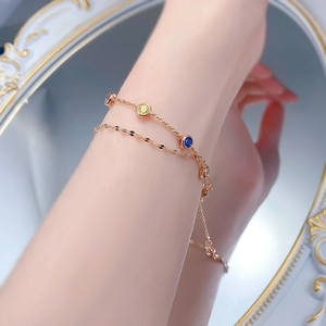 Close-up of double-layer rose gold bracelet with pink, yellow and blue gems on wrist