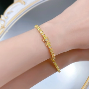 Detailansicht eines 18K vergoldeten Tennisarmbands mit gelben Edelsteinen am Handgelenk