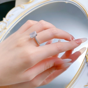 Detailed view of rectangle cut carbon diamond ring on hand with mirror reflection background