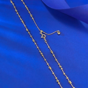 Detailed macro shot of S925 hallmark on gold beaded necklace with heart charm