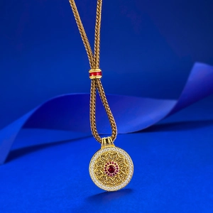 Close-up of S925 silver compass pendant with central red gemstone and woven rope