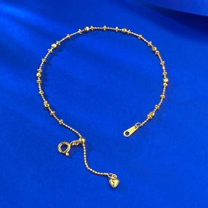 Close-up of S925 sterling silver gold bracelet with heart charm on blue silk