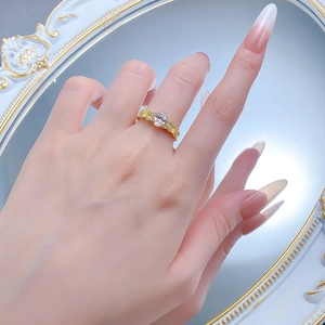 Macro view of gold-plated oval ring featuring clear center stone and small side diamonds