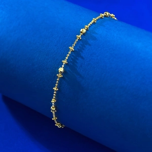 Close-up of S925 silver beaded chain with faceted gold beads on a blue display