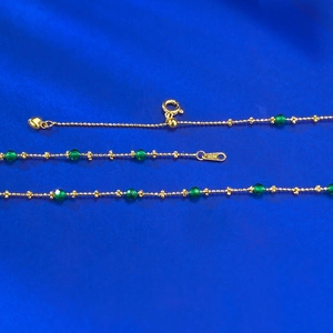 Detail of S925 hallmark on gold beaded chain with green faceted gems and heart pendant