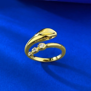 Macro detail of gold snake open ring featuring three graduated white zircon gemstones